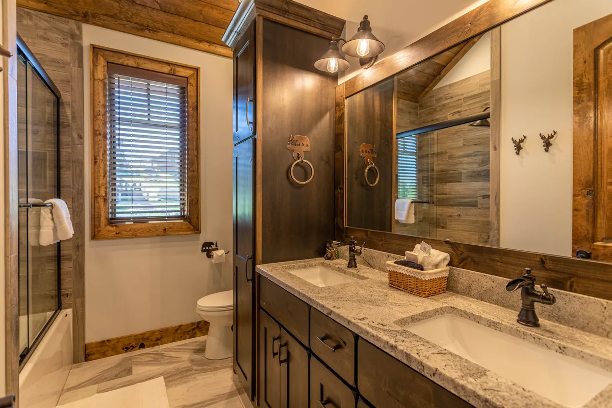 A spacious ensuite bathroom featuring dual sinks with wooden cabinetry, a large mirror, and a sleek glass shower enclosure. The room offers a harmonious blend of functionality and comfort, perfect for daily routines and relaxation.